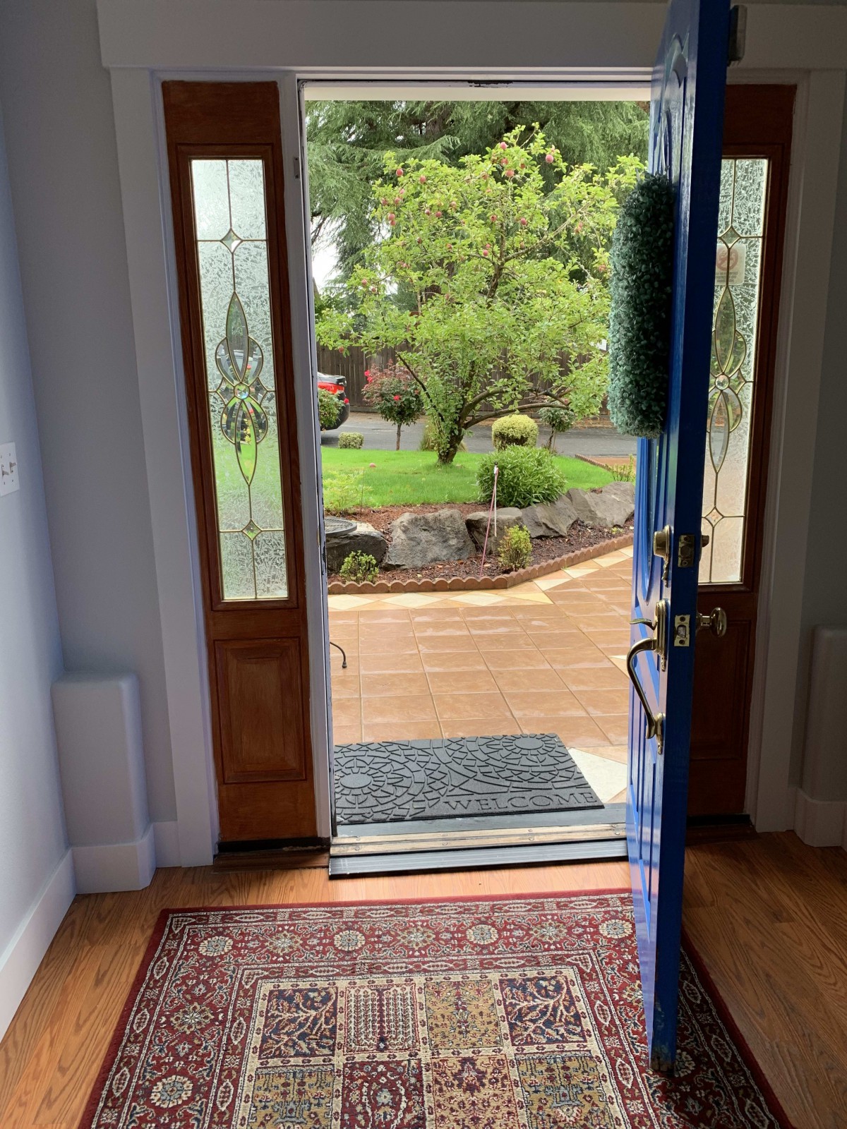 An inviting entryway with an open door leading to a garden view, featuring a decorative rug.