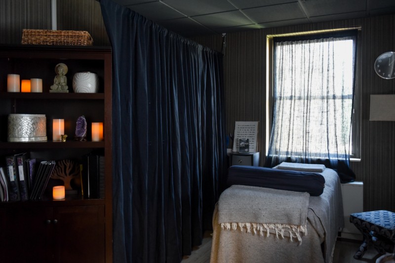 A tranquil massage room with soft lighting, a comfortable bed, and calming decor.