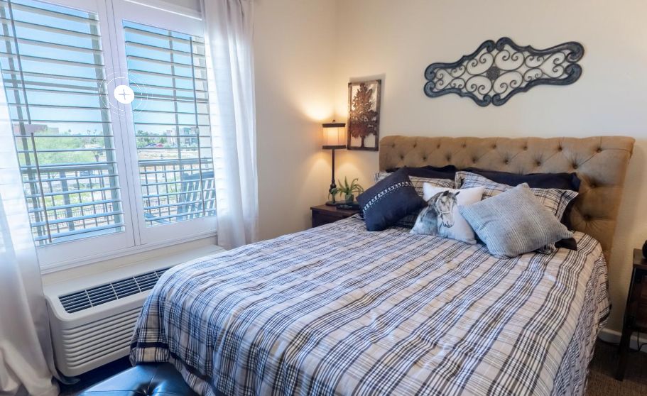 A cozy bedroom with a neatly made bed, decorative pillows, and soft lighting.