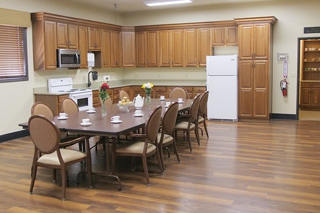A kitchen and dining area featuring wooden cabinets, a large table with chairs, and standard kitchen appliances.