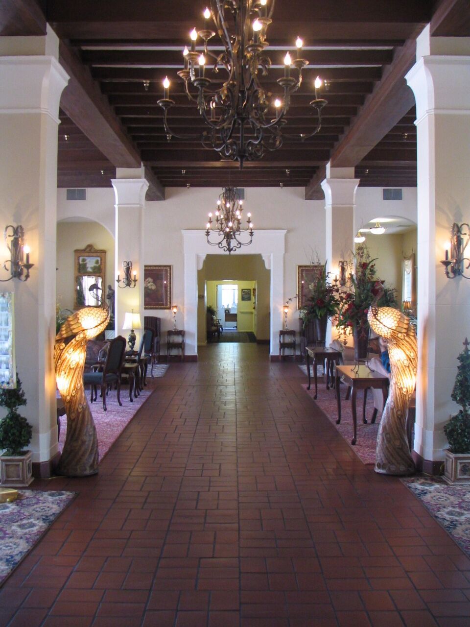 A traditional lobby with chandeliers, seating areas, and decorative lamps.