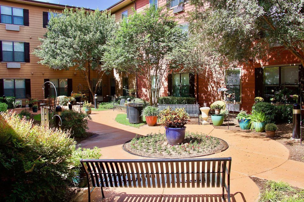 A peaceful courtyard garden with benches surrounded by trees and potted plants.