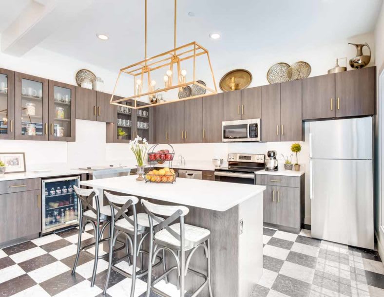 A modern kitchen with a central island, bar stools, and decorative elements on top of cabinets.