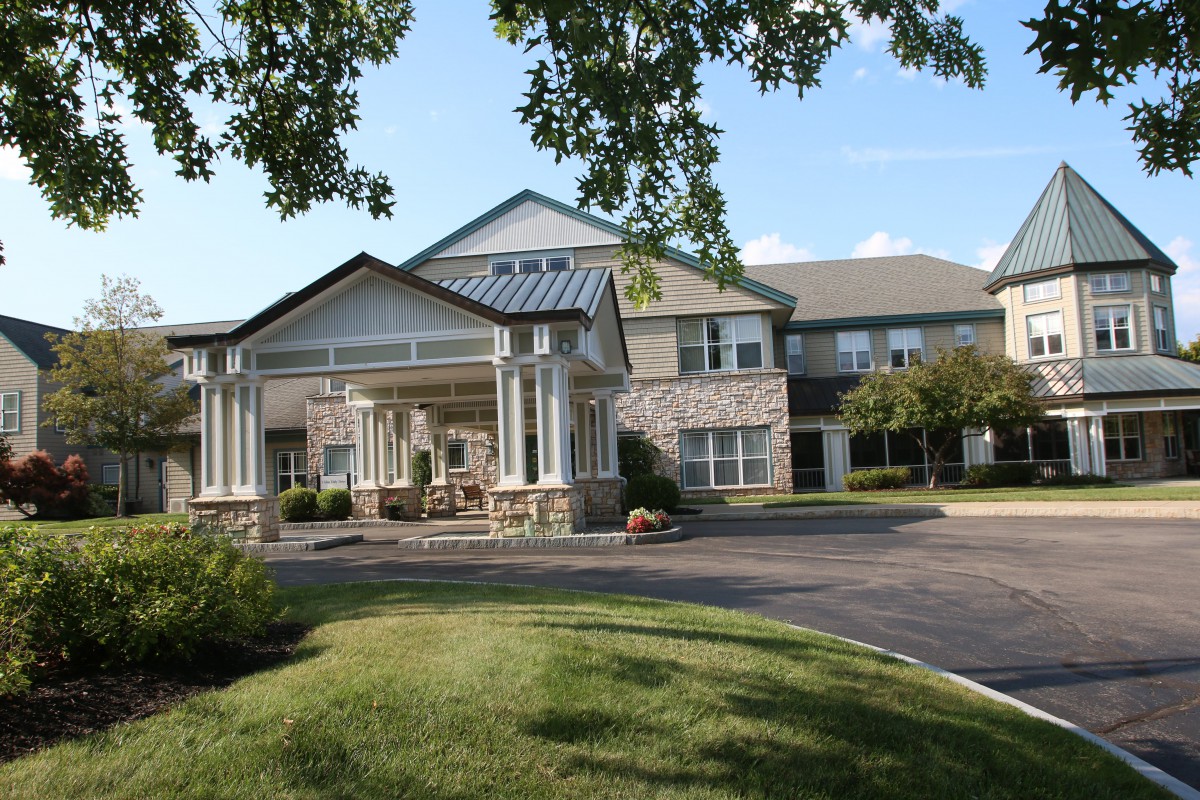 A modern residential building with a landscaped driveway and trees.