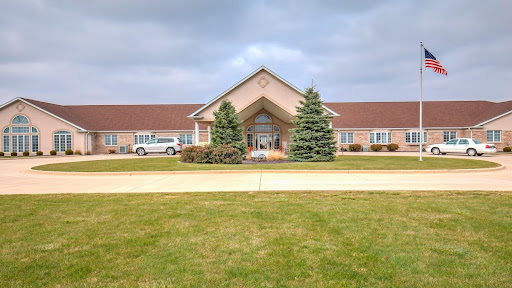 A welcoming entrance to a facility surrounded by neatly manicured lawns and trees under a cloudy sky.