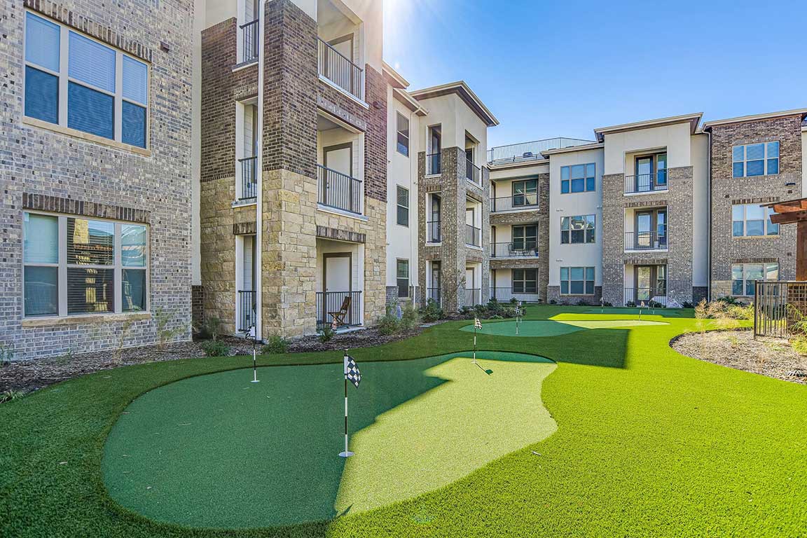 A modern apartment complex featuring a well-maintained putting green.