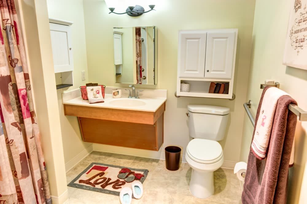 A clean and organized bathroom with a sink, toilet, and mirror.