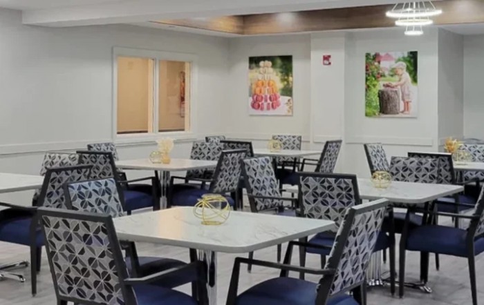 A well-lit dining area with neatly arranged tables and chairs, featuring decorative wall art.