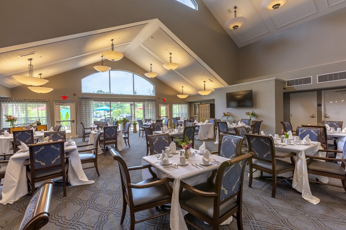 An elegant and spacious dining room with well-decorated tables and chairs, illuminated by ample natural light.