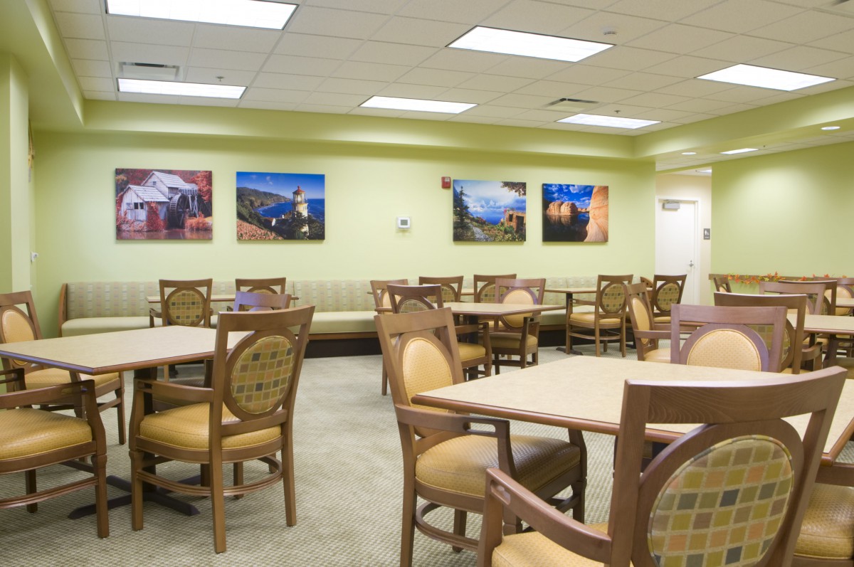 An empty cafeteria with tables and chairs, decorated with artwork on the walls.