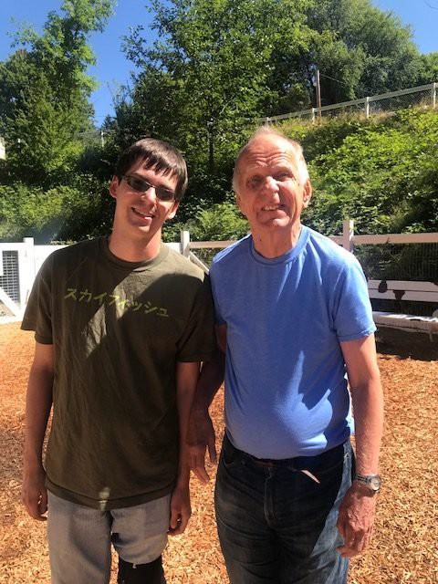 Two people standing outdoors on a sunny day.