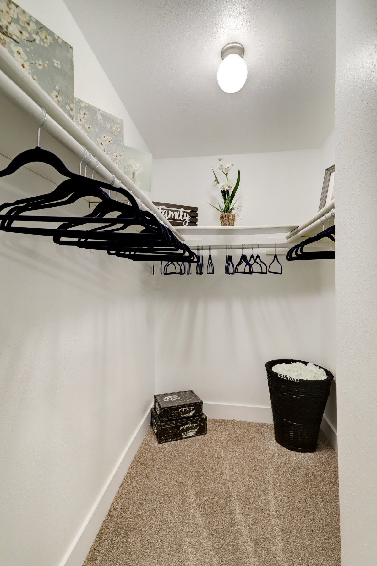 A neatly organized walk-in closet with black hangers and a wicker basket.