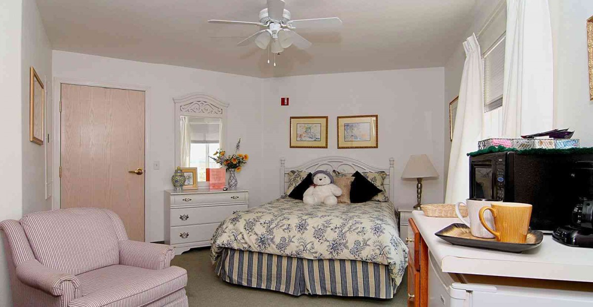 A cozy bedroom with floral bedding and decorative elements.