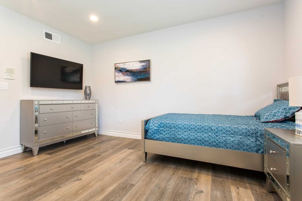 A modern, minimalist bedroom with a single bed and wooden flooring.