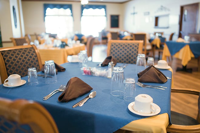 A neatly set dining table with blue tablecloth and brown napkins in a restaurant.