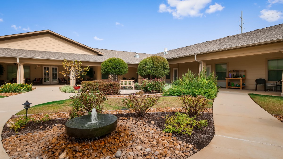 A serene garden courtyard with a small fountain and well-maintained landscaping.
