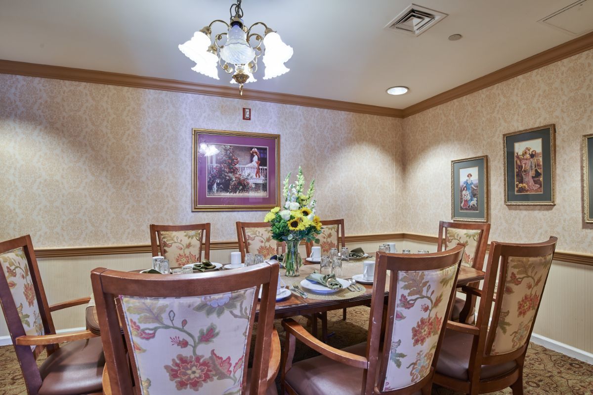 An elegant dining room with floral chairs and a decorated table set under a chandelier.