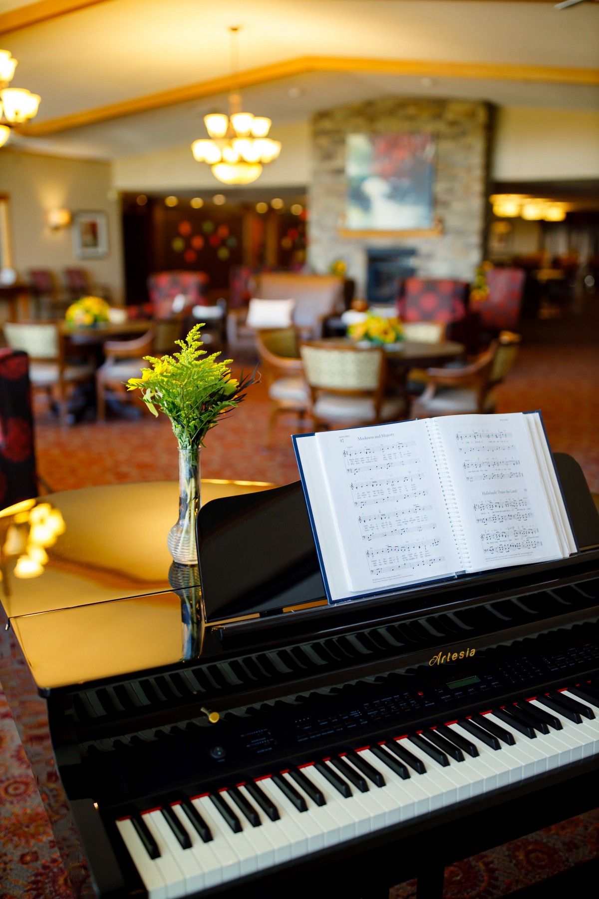 A cozy lobby featuring a piano with an open music sheet and a vase of flowers.