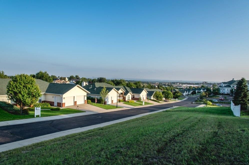 A peaceful suburban neighborhood with rows of houses under a clear blue sky.