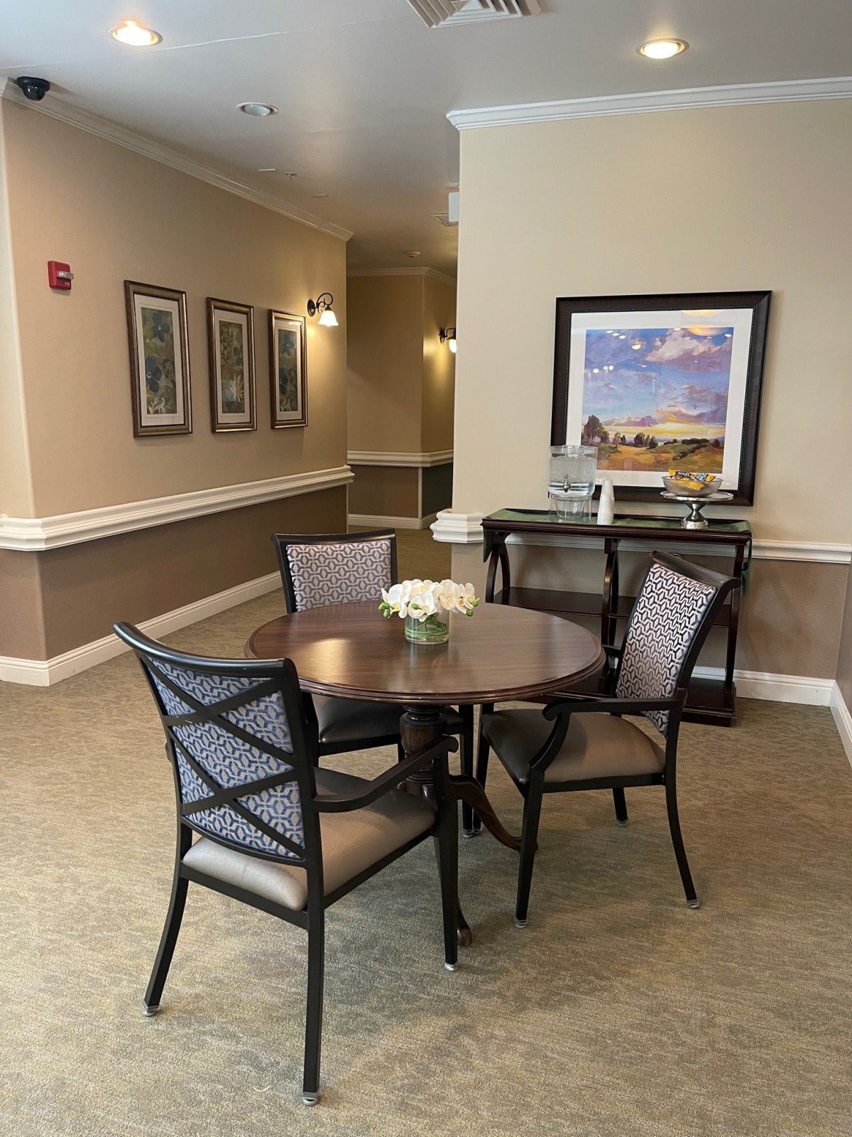 A cozy seating area with a round table and four chairs in a warmly decorated hallway.