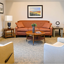 A cozy living room featuring a comfortable orange sofa, two armchairs, and a coffee table, adorned with decorative items.