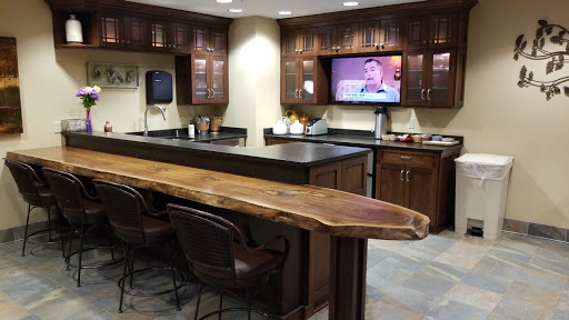 A modern kitchen area featuring a wooden counter, bar stools, and a flat-screen TV, perfect for casual gatherings.