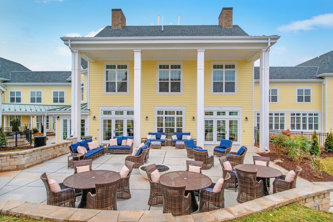 A charming yellow building with a spacious outdoor patio featuring tables and cushioned seating.