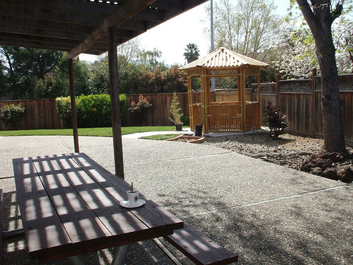 A serene backyard with a gazebo, picnic table, and well-maintained garden.
