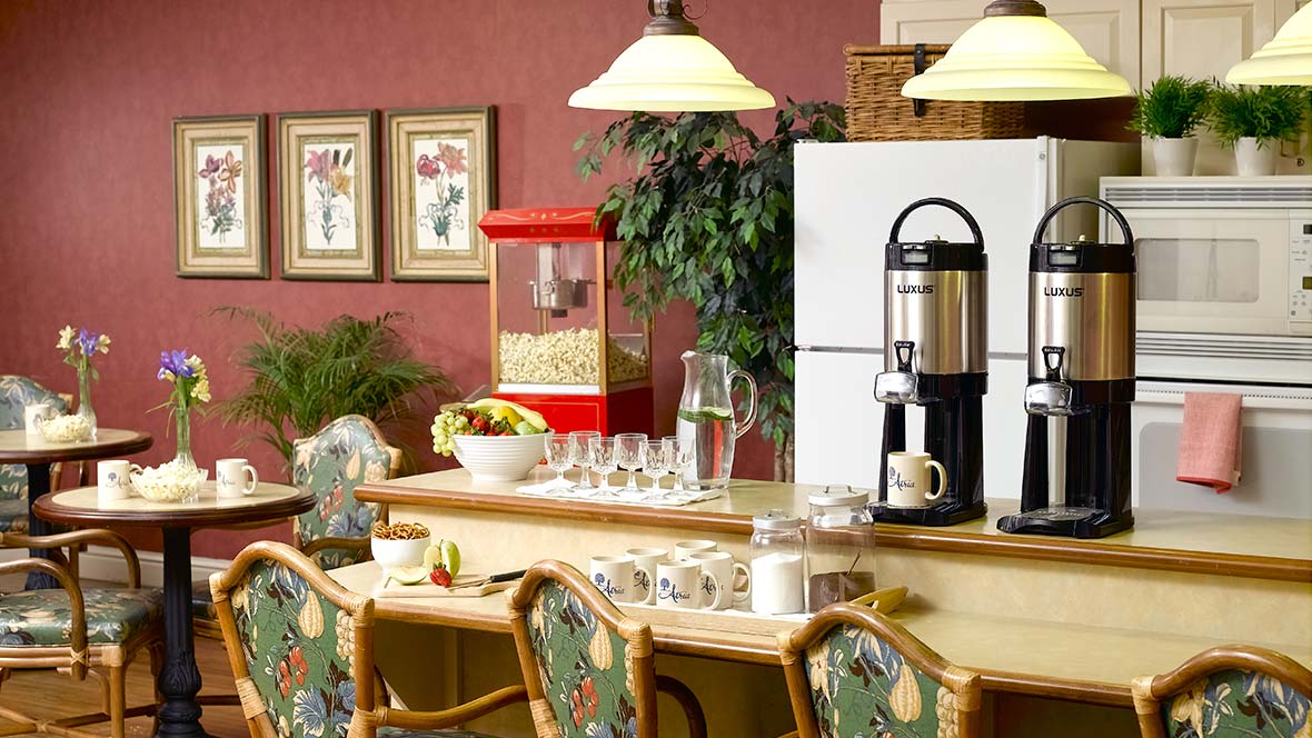 A cozy dining area featuring a coffee maker, popcorn machine, and table set with glasses and cups.