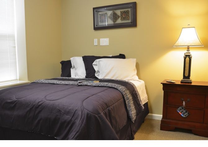 A cozy bedroom with neatly arranged bedding and a warm bedside lamp.
