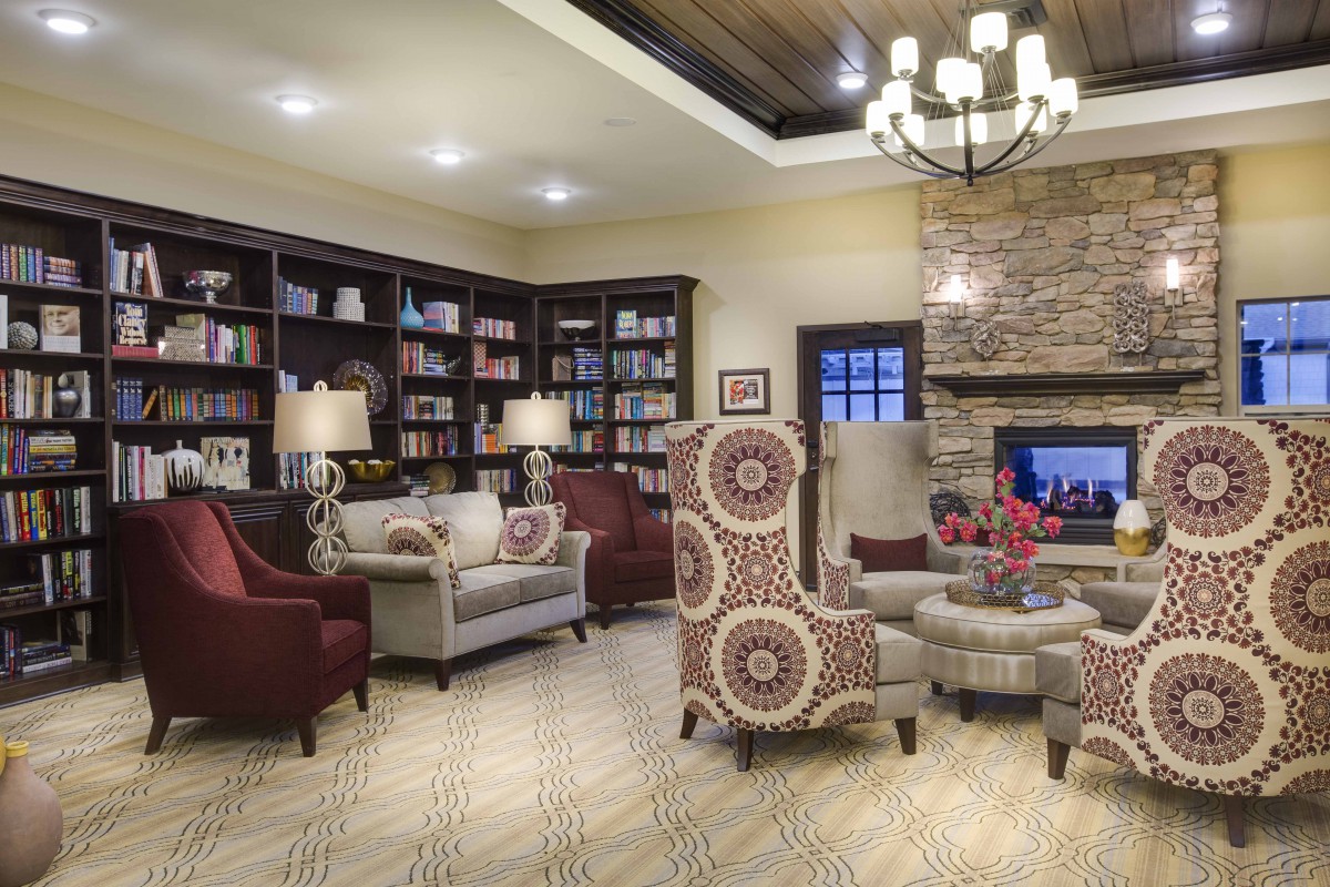 A cozy living room with elegant furniture, a fireplace, and bookshelves.