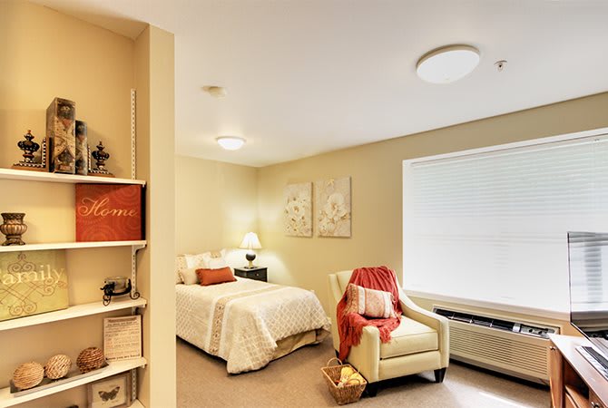 A cozy and minimalist bedroom with a comfortable bed, armchair, and simple decor.