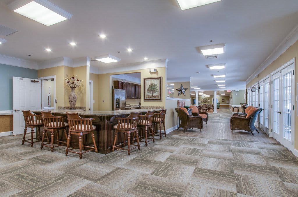A spacious and modern lounge area with a bar, stools, and comfortable seating.