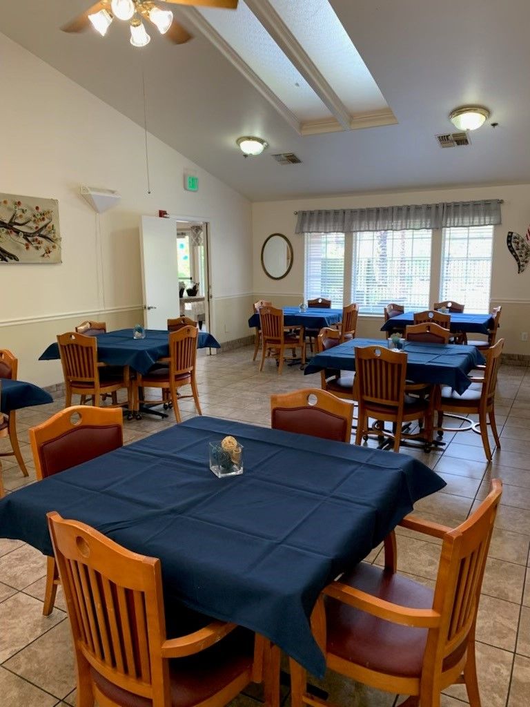 A cozy dining area with neatly arranged tables and chairs, adorned with blue tablecloths.