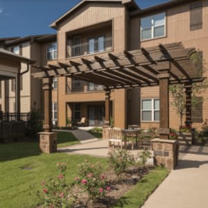 A modern apartment building with a pergola and landscaped garden.