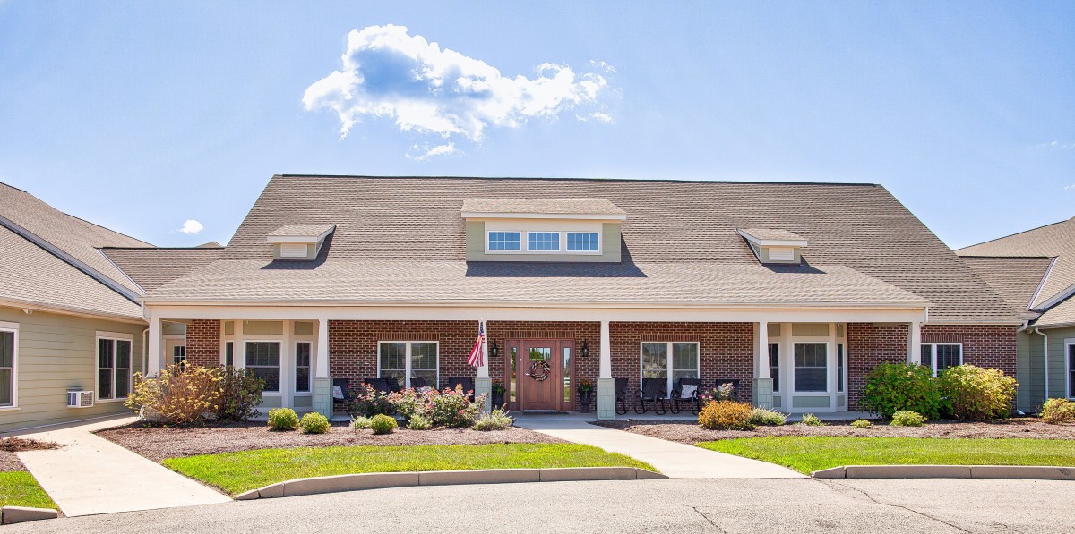 A charming residential building with a front porch and well-maintained landscaping under a clear blue sky.