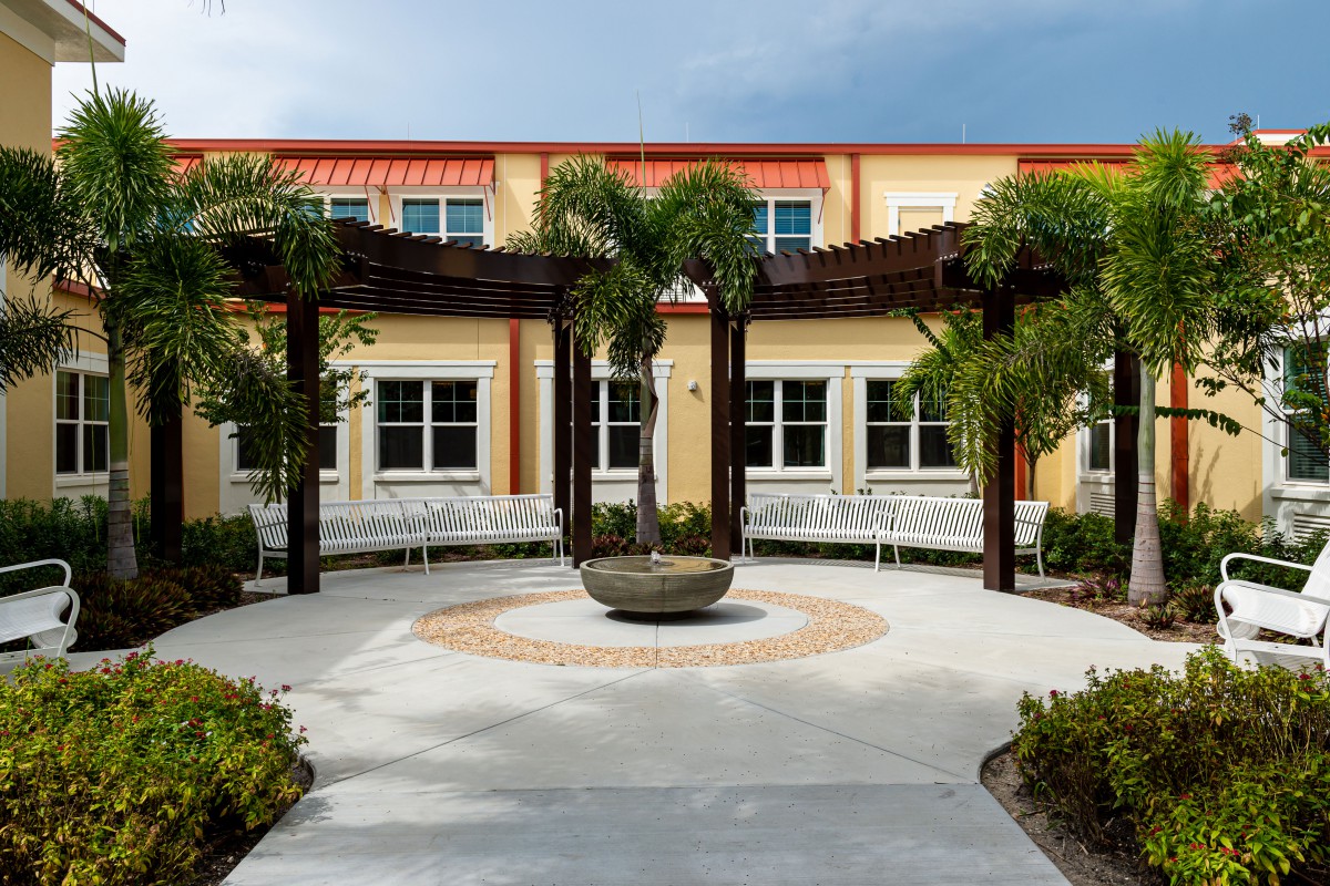 A scenic courtyard with palm trees and a central architectural feature in front of a building.