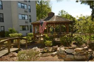 A wooden gazebo in a garden setting with an American flag displayed.