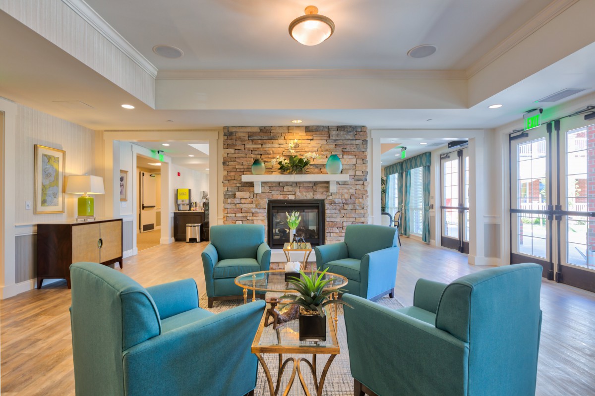 A cozy living room with teal chairs arranged around a fireplace, creating a warm and inviting seating area.