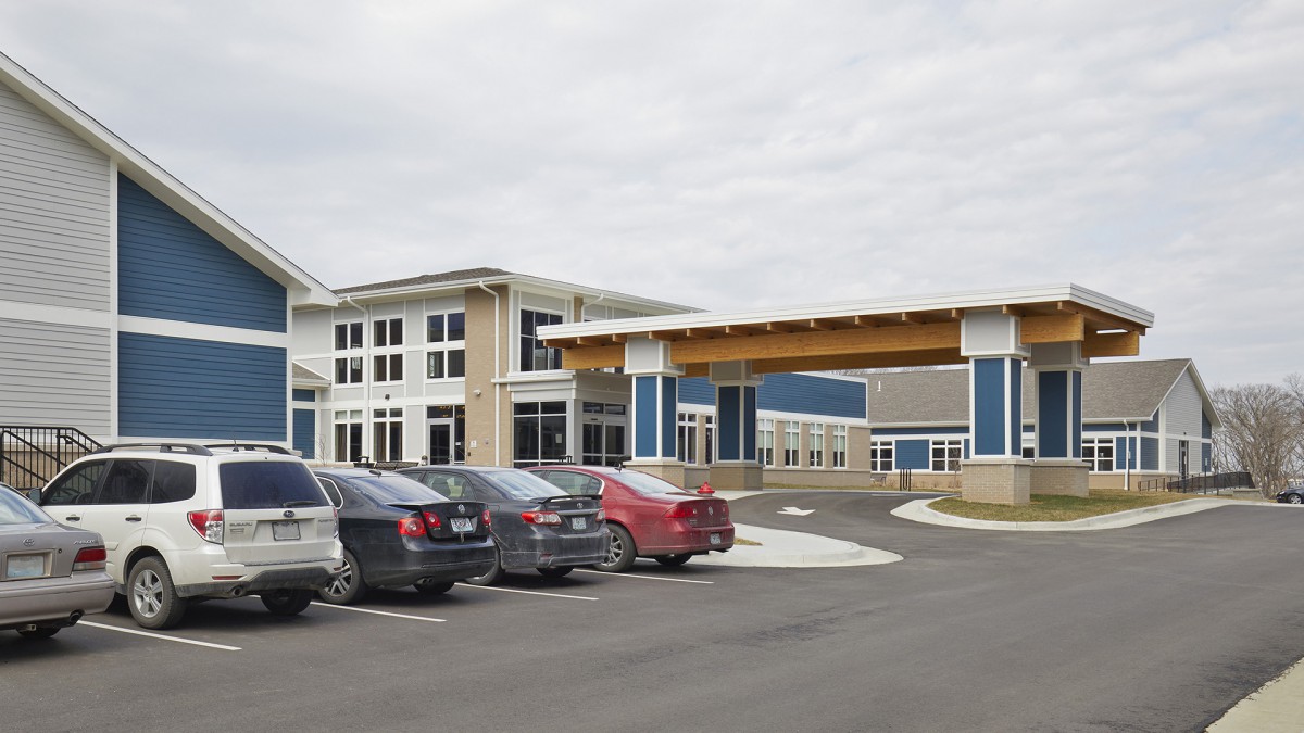 A modern commercial building with an adjacent parking lot filled with cars.
