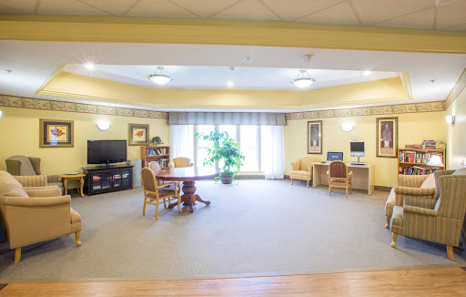 A spacious and bright common area featuring comfortable seating, a desk, and a television.