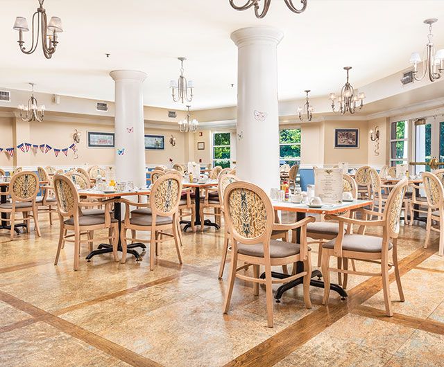 An elegant and empty restaurant interior featuring wooden tables and chairs with decorative chandeliers.