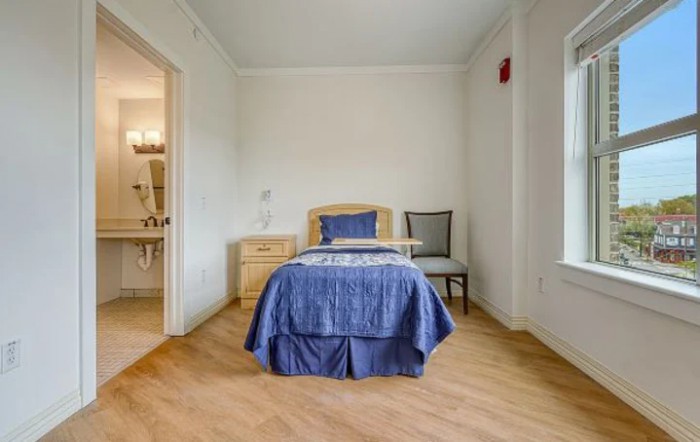 A minimalist bedroom with a single bed and wooden flooring.