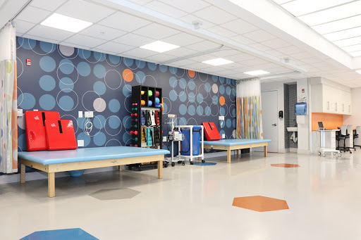 A brightly colored therapy room designed for rehabilitation, featuring equipment and spacious treatment areas.