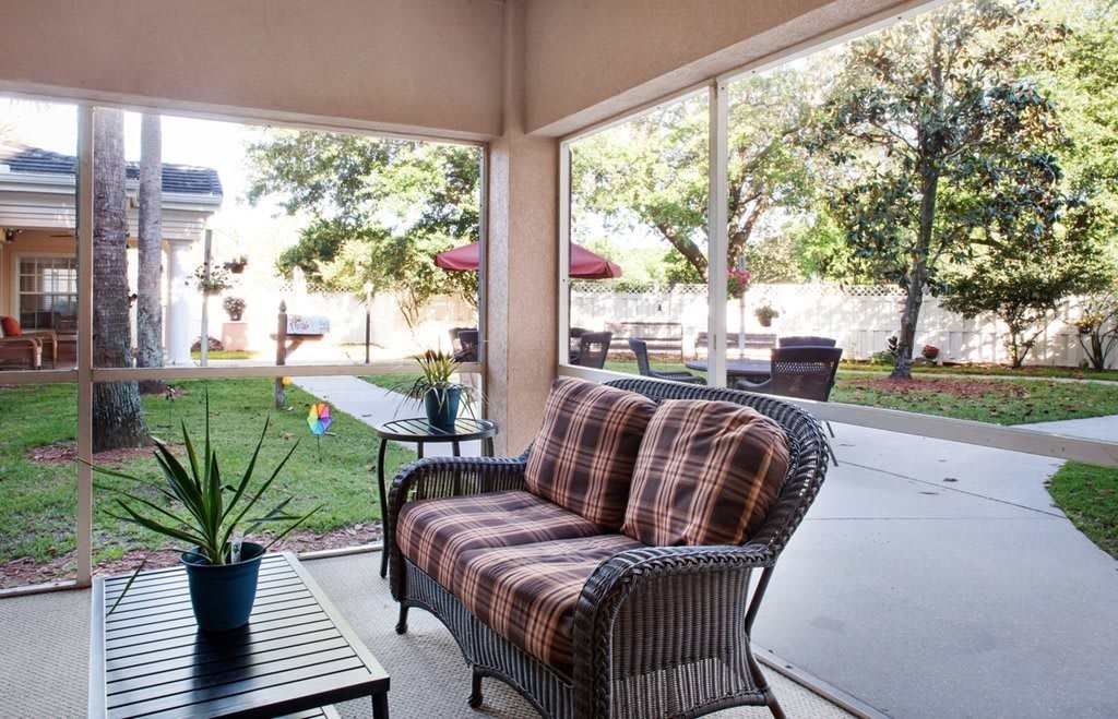 A cozy patio with comfortable wicker furniture and a view of a lush garden.