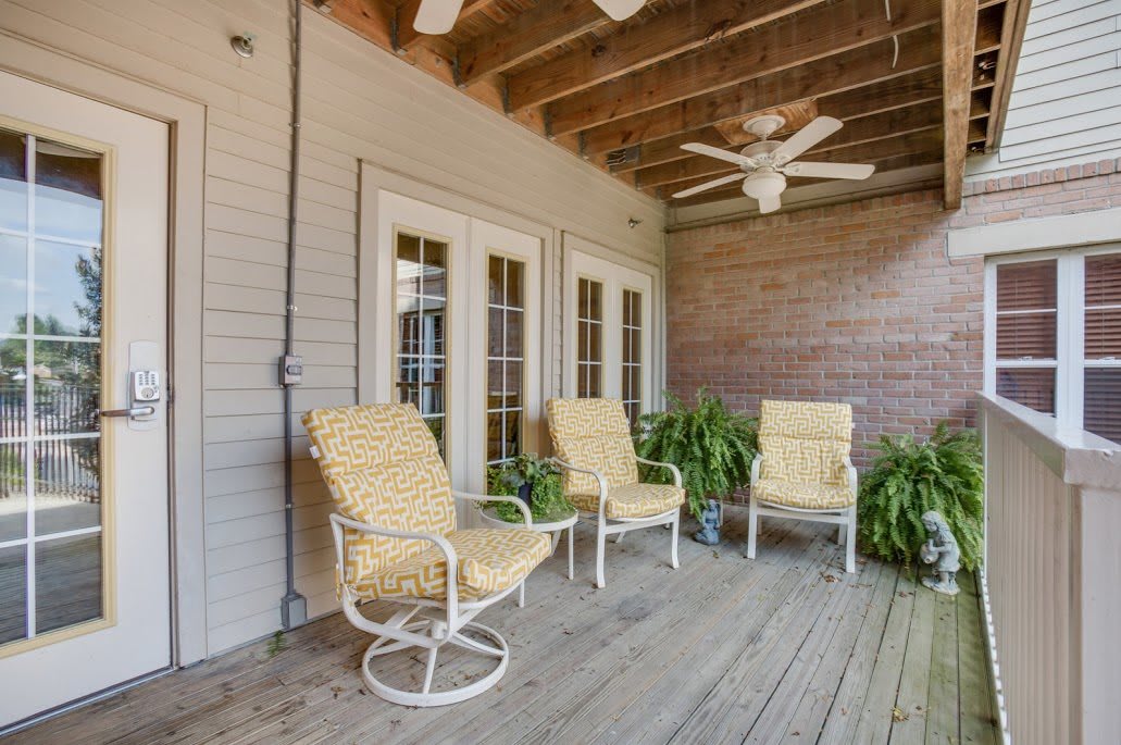 A cozy porch with comfortable seating and a ceiling fan.
