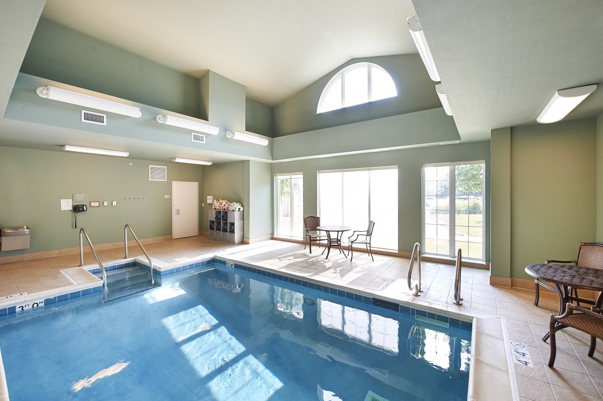 A bright indoor swimming pool area with large windows and a seating area.