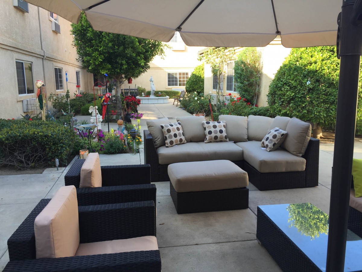 A cozy patio with outdoor seating, surrounded by a neatly landscaped garden.