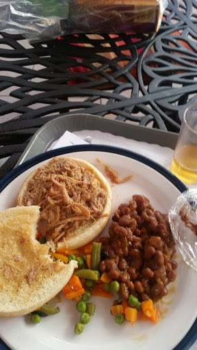 A delicious meal featuring pulled pork, beans, cornbread, and assorted vegetables.