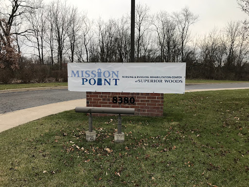 A sign for Mission Point, set against a backdrop of trees and grass.